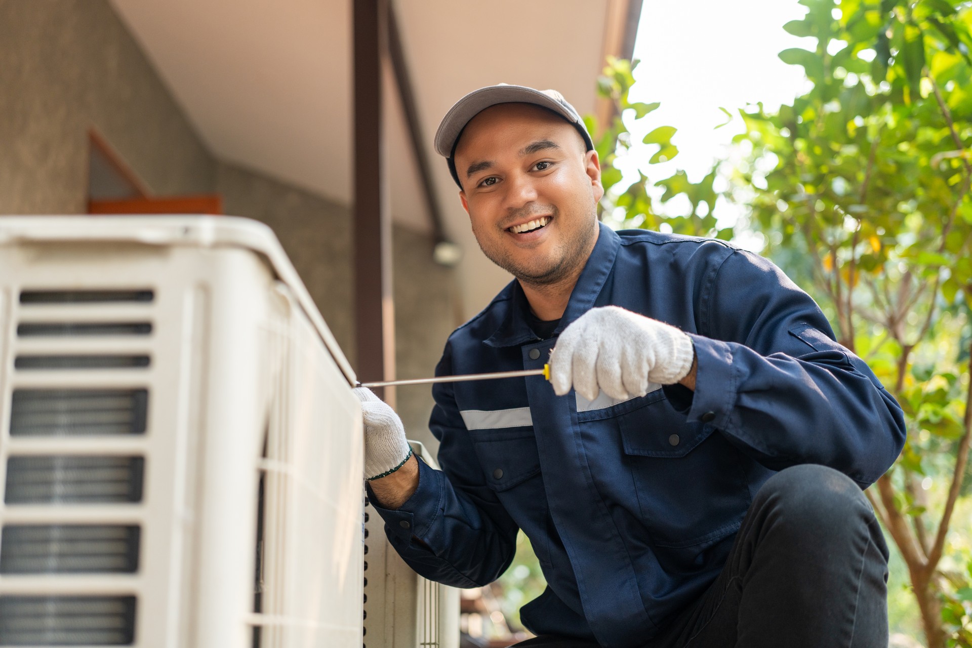 Air conditioner service outdoor checking fix repair. Air conditioner cleaning technician He opened the front cover and took out the filters and washed it. He in uniform wearing rubber