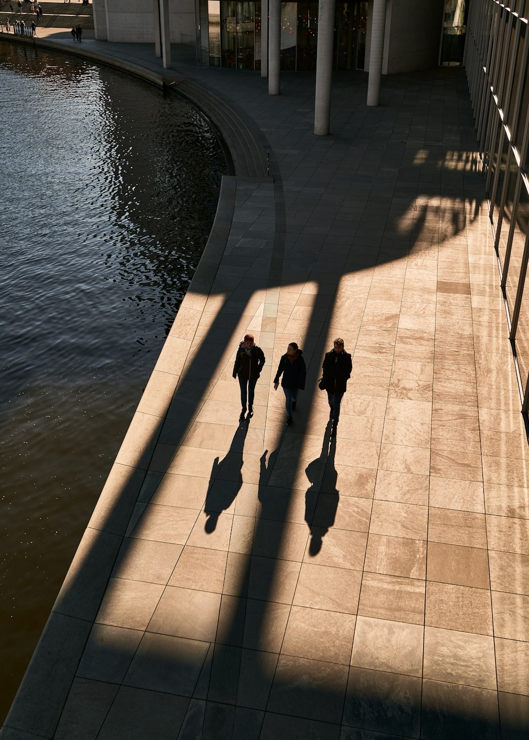 a group of people walking down a sidewalk next to a body of water